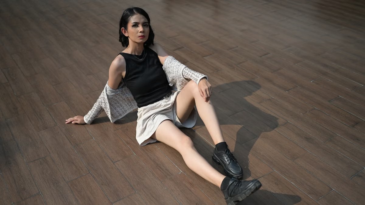 Fashionable young woman sitting on a wooden floor in Jakarta, displaying modern style and confidence.
